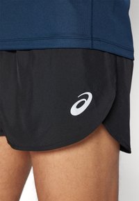 Schwarze Sportshorts mit abgerundetem Saum, aus leichtem Material gefertigt. Enthält ein weißes Logo-Akzent auf der unteren linken Seite.