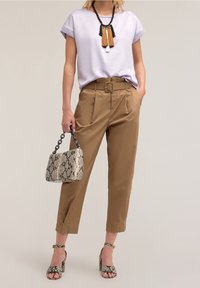 Top lila de mangas cortas, pantalones marrones de cintura alta con cinturón, bolso de piel de serpiente y tacones a juego con tiras en los tobillos. Textura suave.