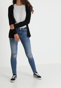 Black open cardigan, gray t-shirt, light blue skinny jeans with distressed knee rips, black and white sneakers. Simple, casual outfit.