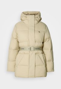 Beige puffjacka med huva, kviltat mönster, bälte i midjan och två framfickor. Har en subtil logotyp på bröstet och en slät yta.