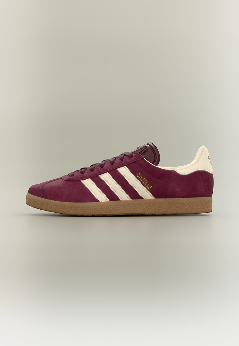 Bordó színű, nubuk bőr Adidas Gazelle sportcipő krémszínű csíkokkal és sarokpánttal, gumitalppal, semleges háttéren kiállítva.