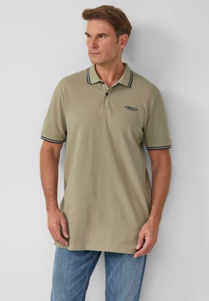 Khakifarbendes Poloshirt mit einem gerippten Kragen, der blaue Streifen aufweist, kurzen Ärmeln und einem kleinen Logo. Kombiniert mit hellen Jeans.