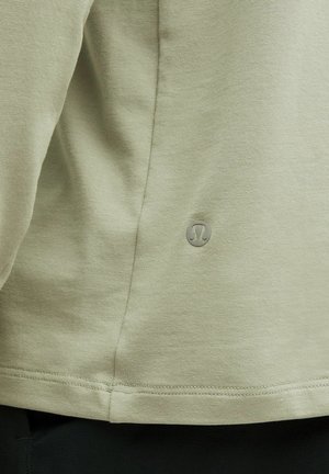Maglietta sportiva verde chiaro con una texture liscia. Include un piccolo logo e dettagli di orlo cuciti, adatta per l'abbigliamento casual o per l'esercizio.