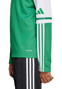 Groen sportshirt met lange mouwen, voorzien van witte accenten en drie verticale strepen. Gemaakt van vochtafvoerend materiaal, gelabeld "AEROREADY."