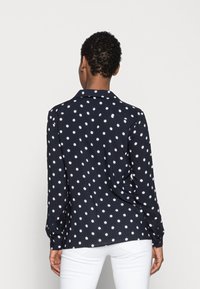 Camicia a maniche lunghe navy con pois bianchi, design con colletto, tessuto morbido, orlo curvo e polsini con bottoni.