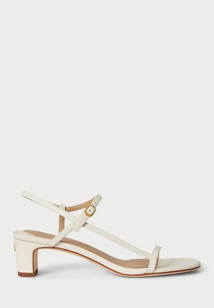 Sandale en cuir blanc avec un petit talon carré, comportant de fines lanières et un détail de boucle. Texture lisse et design minimaliste.