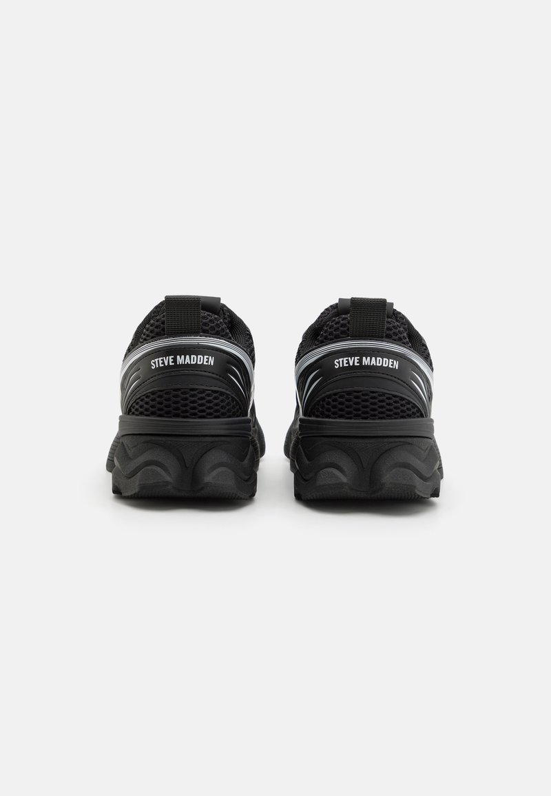 Baskets de sport en mesh noir avec de grosses semelles en caoutchouc et un logo à l'arrière. Présentent une surface texturée et un design de semelle courbée distinct.