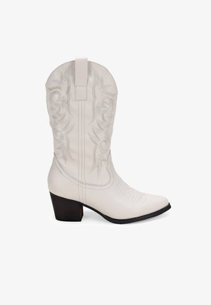 Botte de cowboy en cuir blanc avec des motifs brodés décoratifs, bout pointu et un talon bloc de hauteur intermédiaire. Anse en haut pour un enfilage facile.