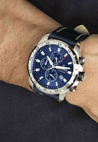 Reloj cronógrafo con esfera azul marino, caja en tono plateado, marcadores blancos y correa de cuero. Cuenta con tres subesferas y pantalla de fecha.