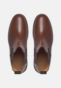 Bottines chelsea en cuir marron avec des panneaux latéraux élastiques et des languettes. Fini lisse, bout arrondi et détail de couture subtil.