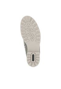 Suela de zapato con un diseño de goma texturizada en gris claro que presenta múltiples patrones de tracción y un área de logo en relieve.