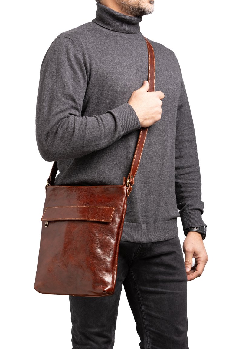 Borsa a tracolla in pelle marrone con una texture morbida, dotata di un'unica tracolla regolabile e di una tasca frontale con patta. Presenta cuciture a contrasto.