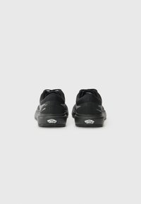 Black athletic shoes with a smooth textile upper, reinforced heel, and cushioned sole. Features branding at the heel and tongue.
