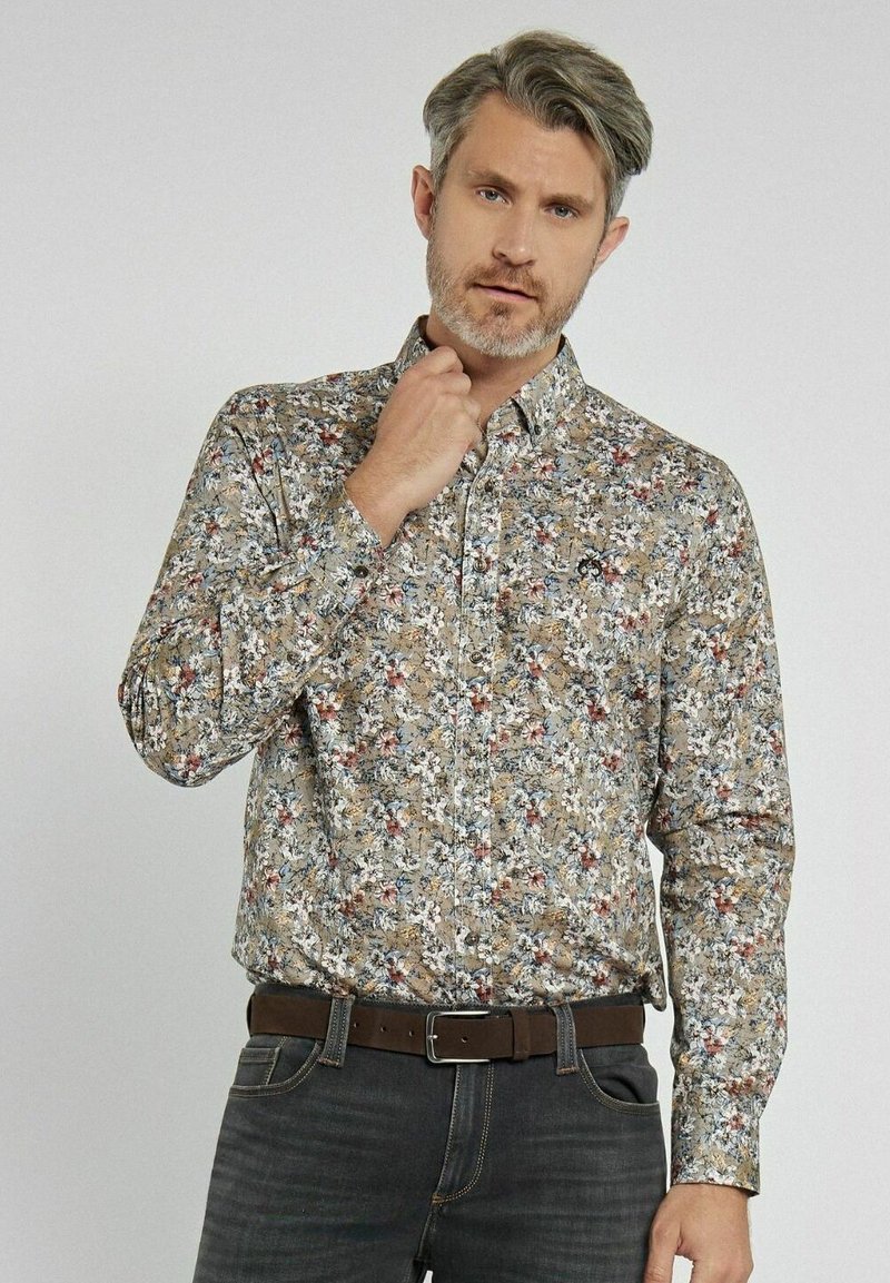 Koszulka z długim rękawem i wzorem w kwiaty w odcieniach beżu, niebieskiego i czerwonego. Standardowy kołnierzyk, zestawiona z ciemnymi dżinsami.