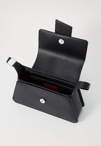 Zwarte leren handtas met een open klep, zilveren druksluiting en binnenvakken. Voorzien van een logotag en een gestructureerd materiaal.