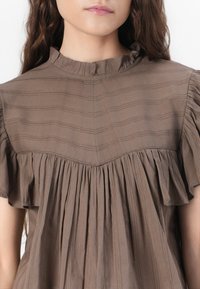 Bruine blouse van zachte stof, met een gerimpelde halslijn, verticale strepen en geplooide details bij de mouwen en het lijfje.