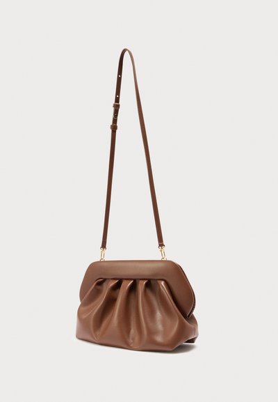 Καφέ δερμάτινη τσάντα ώμου με πλισέ σχέδιο και ρυθμιζόμενο λουρί, σε απλό ανοιχτό φόντο.