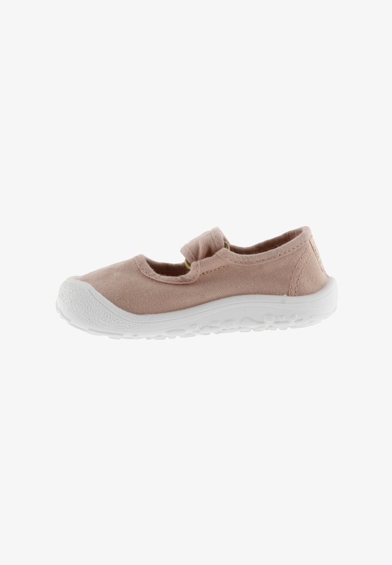 Zapatilla de lona de color rosa claro con suela de goma blanca, punta redondeada y tira elástica. Presenta un diseño simple y un material superior texturizado.