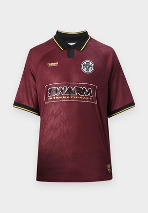 Bordo nogometni dres s črnim ovratnikom in rumenim robom, napis "SWARM INTERNATIONALS" čez prsni koš in krožni grb ekipe na levi strani prsnega koša.