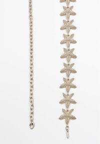 Metalarmbånd med strukturerede søstjernemotiver i en guldtonet finish, med kæde og lås.