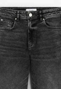 Jean en denim noir avec un design classique à cinq poches, fermeture à bouton sur le devant, et un léger délavage pour la texture. Étiquette de la marque visible à la taille.