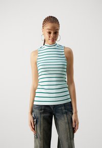 Top sin mangas azul claro con rayas horizontales verde oscuro, textura acanalada y escote alto. Combinado con pantalones de mezclilla azul de corte holgado.