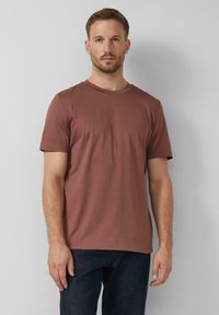 Pánske tričko s krátkym rukávom v červeno-hnedej farbe, vyrobené z mäkkej tkaniny, s okrúhlym výstrihom a voľným strihom.