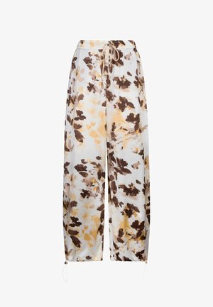 Pantalon à jambes larges crème avec imprimé floral abstrait marron et beige, taille élastique avec cordon de serrage, et liens ajustables à la cheville.
