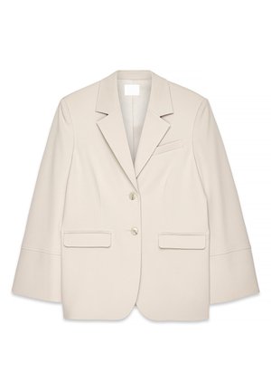 Beige skräddarsydd kavaj med slagkrage, två framfickor och två knappar. Har strukturerade axlar och en boxig silhuett.