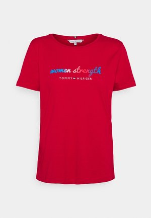 Czerwona koszulka z krótkim rękawem i okrągłym dekoltem, z napisem "women strength" w kolorze niebieskim i różowym oraz logo "Tommy Hilfiger" poniżej na przodzie.
