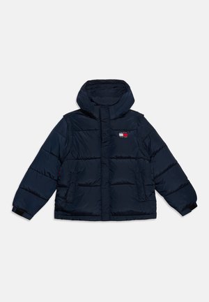 Granatowa pikowana kurtka z kapturem, przednimi kieszeniami i logo Tommy Hilfiger na piersi, położona płasko na białym tle.