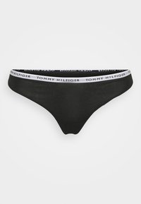 String noir avec une ceinture élastique blanche arborant le texte "TOMMY HILFIGER". Tissu lisse avec une coupe ajustée et sans motifs supplémentaires.