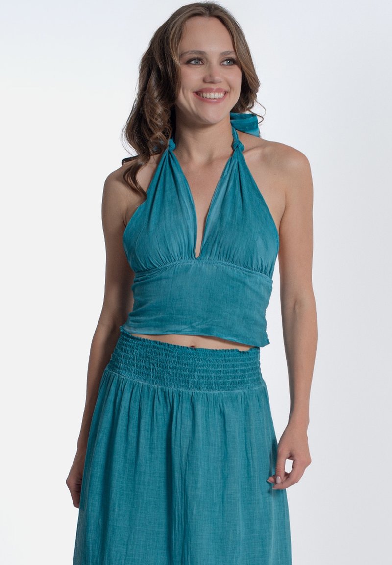 Top corto halter turchese con scollo arricciato e spalline da legare, abbinato a una gonna smock coordinata con una silhouette fluida.