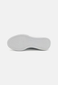 Semelle de sneaker blanche avec une surface en caoutchouc texturée. Présente un motif en chevrons pour l'adhérence et la marque "SKECHERS" estampillée sur le côté.