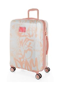 Maleta rígida en blanco con patrones de grafiti en color melocotón. Cuenta con un asa rosa, cremallera y cuatro ruedas multidireccionales para facilitar la movilidad.