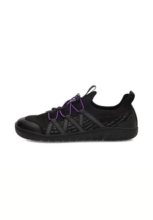 Zapato deportivo negro de perfil bajo con cordones elásticos morados, empeine de tela tejida y suela de goma texturizada, mostrado de lado sobre un fondo blanco.