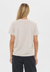 Beige cotton t-shirt with short sleeves and a round neckline, featuring a plain back and a relaxed fit. No visible patterns or accents.
