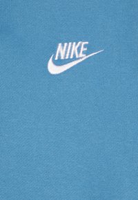 Zila kokvilnas auduma ar gludu tekstūru, uz kura kreisajā pusē ir balts izšūts Nike logo. Vienkāršs dizains, bez papildu rakstiem.