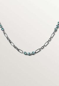 Collar de cadena de plata con eslabones ovalados alternos y piedras preciosas azules redondas engastadas en acentos de plata. Textura suave con un brillo metálico.