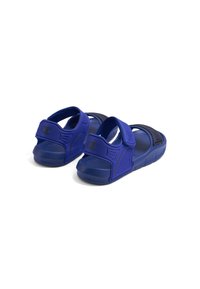 Sandali blu con parte superiore testurizzata, strap per regolazione e suole imbottite. Presentano un accento con logo sulla fascia, progettati per il comfort.