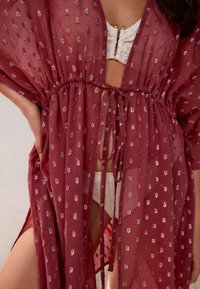 Vínový priehľadný kimono s opaskom na zaväzovanie v páse, zdobený textúrovaným vzorom z drobných kovových akcentov po celej ploche. Ľahká a vzdušná látka.