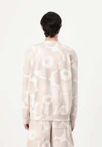 Hellbeige Sweatshirt mit großem Blumenmuster in sanften Farbtönen. Rundhalsausschnitt, lange Ärmel, lässige Passform, gerippte Bündchen und Saum.