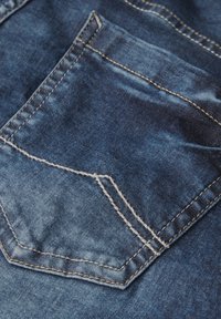 Tissu en denim bleu foncé avec une finition texturée. Comprend une poche arrière avec des coutures blanches et un design en angle distinctif.