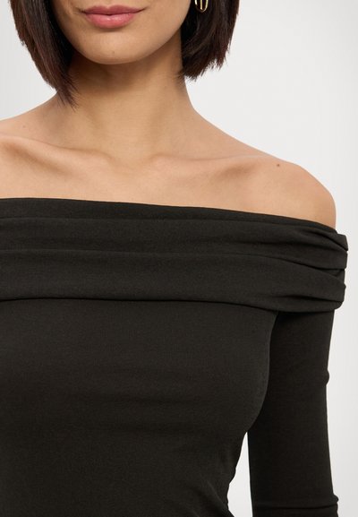 Svart avtagbar off-shoulder topp med en tettsittende design, laget av myk og glatt stoff med rynkedetaljer ved utringningen. Lange ermer fremhever silhuetten.