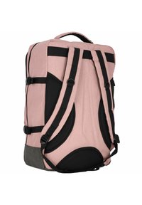 Un sac à dos en tissu rose avec des sangles noires, des accents en maille et un fond gris renforcé. Il dispose d'une poignée supérieure et de boucles latérales ajustables.