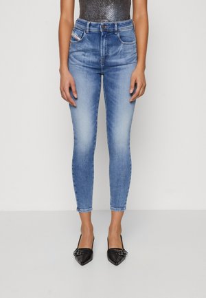 Lyseblå høyhalsede skinny jeans med en falmet effekt, fem lommer, metallknappelukking og ankellengde, kombinert med svarte spisse sko.