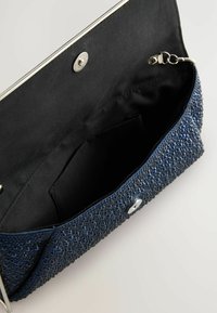 Clutch bag navy con superficie texturizzata e decorata con perline, chiusura a scatto argentata e interno in tessuto nero con una piccola tasca.