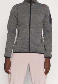 Szara kurtka polarowa z fakturowanym wzorem, pełnym zamkiem błyskawicznym, wysokim kołnierzem i czerwonymi akcentami. Posiada boczne kieszenie na zamek i kieszeń na rękawie.