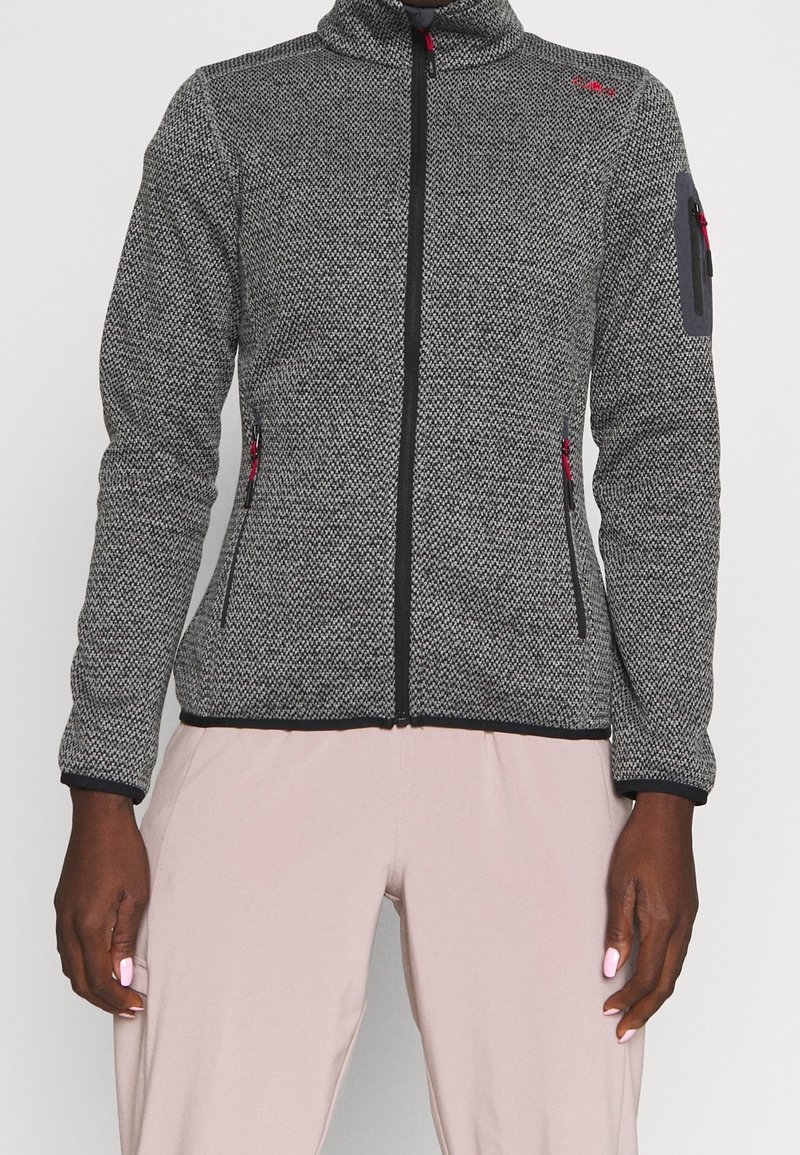 Szara kurtka polarowa z fakturowanym wzorem, pełnym zamkiem błyskawicznym, wysokim kołnierzem i czerwonymi akcentami. Posiada boczne kieszenie na zamek i kieszeń na rękawie.