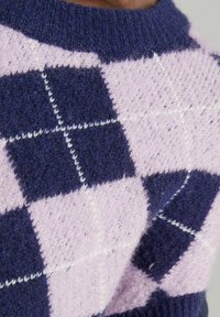 Stickad tröja med ett mönster av lila och marinrutigt, med en mjuk textur och ribbad krage. Vita rutlinjer framhäver designen.